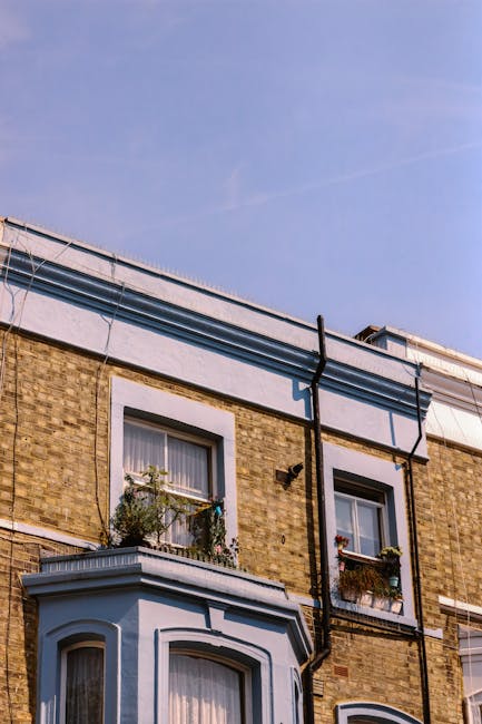 A multi-storey brick building with a weathered exterior, featuring a large, faded sign that reads 'BRIXTON HOUSE' in white capital letters against a brown background, with a smaller red 'X' in the wor